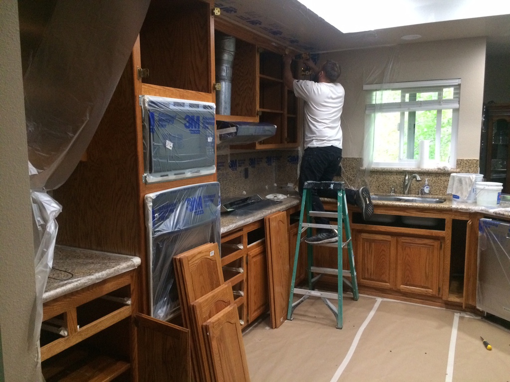 Talbot Painting crew member at work refinishing kitchen cabinets in a Redding home