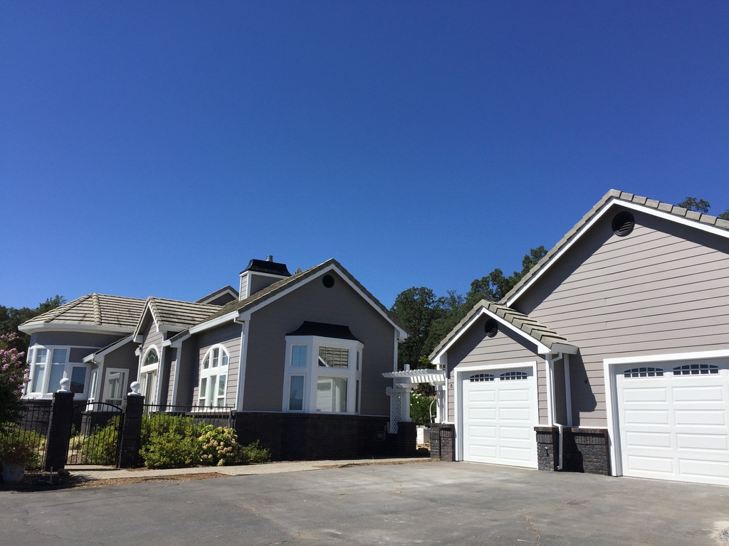 Taupe home and matching detached garage with fresh exterior paint under a blue sky in Redding, California