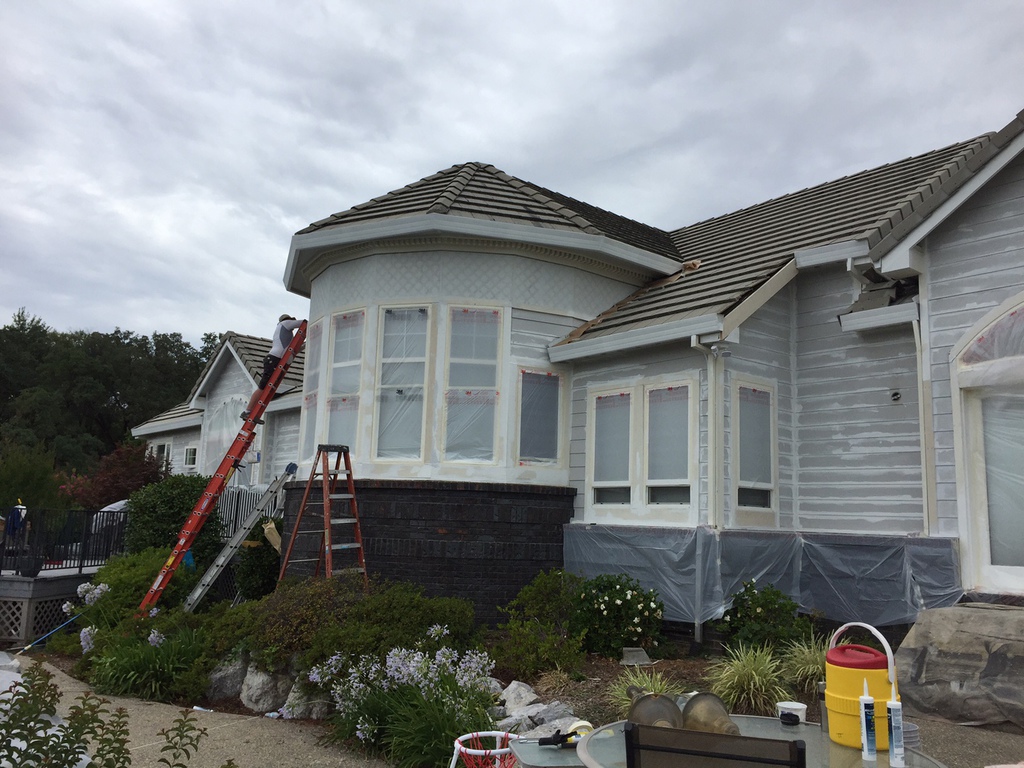 Talbot Painting crew member on a ladder prepping a two-story home exterior for paint in Redding, California