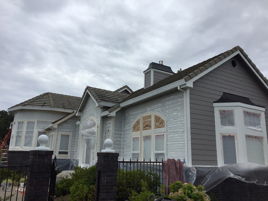 Large two-story Redding home with windows and stonework masked for exterior painting by Talbot Painting