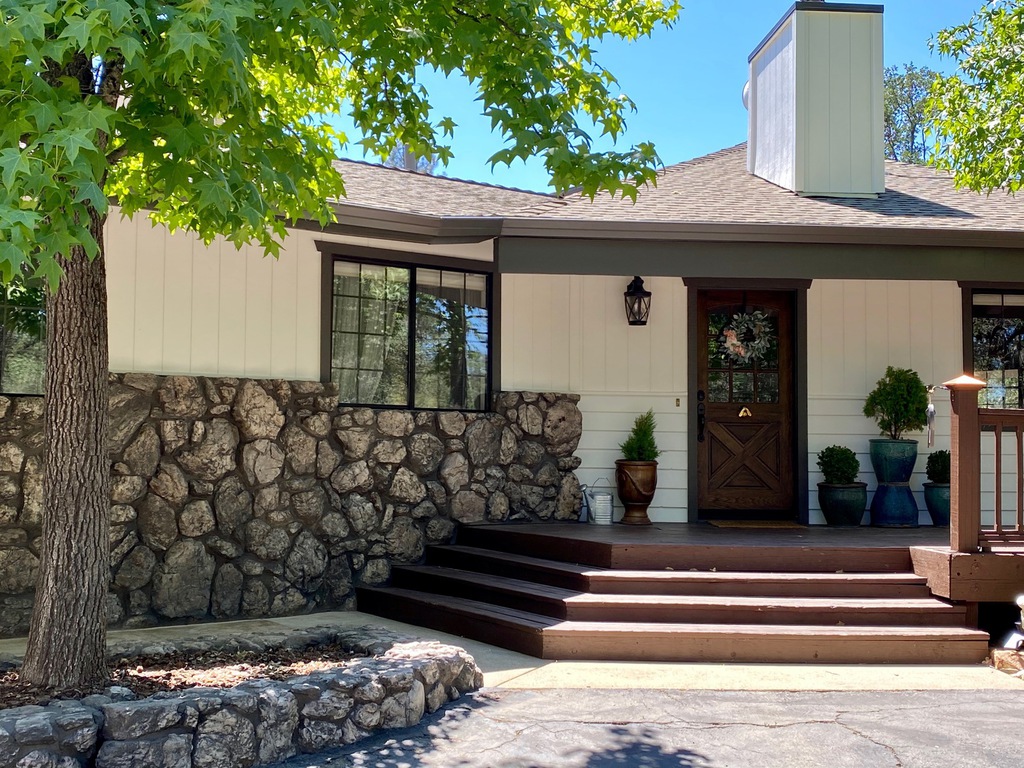 Freshly painted white farmhouse exterior with dark bronze trim and stained front porch in Redding, California