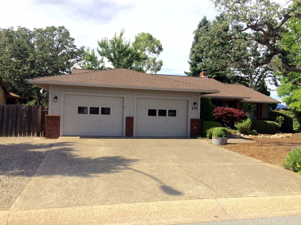 Same Redding garage after exterior painting with fresh taupe siding and clean white doors