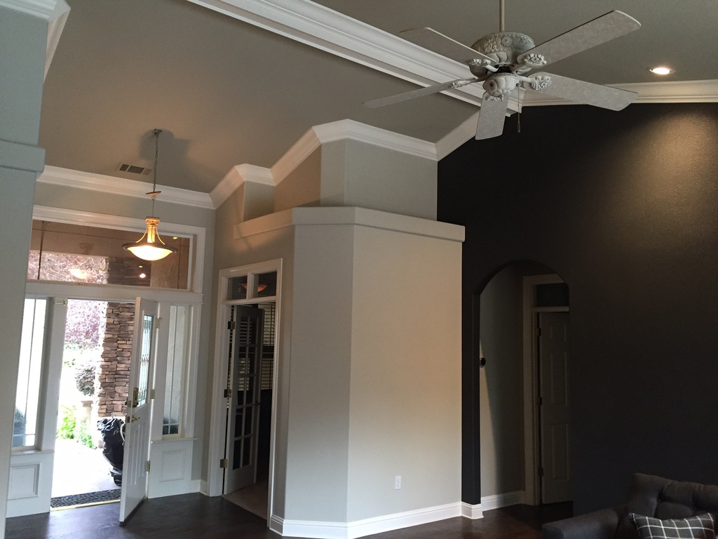 Interior entryway in a Redding home with tall ceilings, dark accent wall and freshly painted white trim and columns