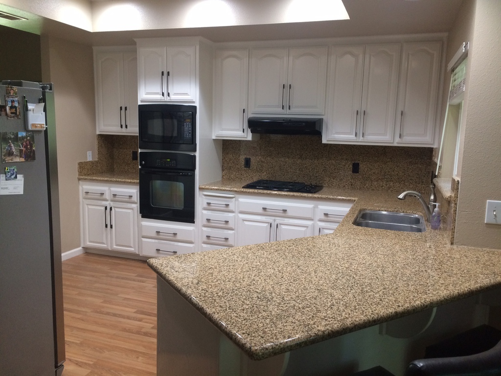 Kitchen with oak cabinets refinished in white by Talbot Painting, granite counters and black appliances