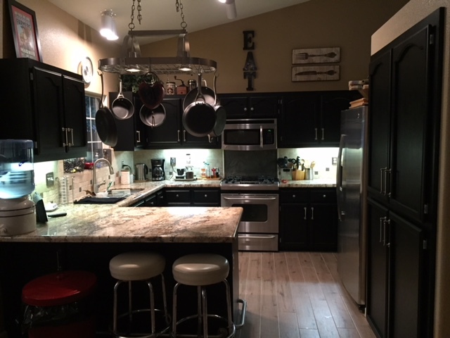 Kitchen cabinets refinished in black with granite island and stainless appliances in a Redding home